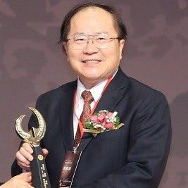 Jin Tan Liu holding an award and smiling at camera